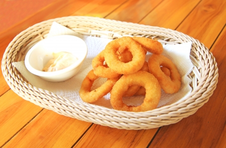 Fried onion rings on absorbent paper in white basketの写真素材