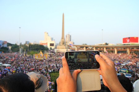 BANGKOK,THAILAND- DECEMBER 22  A protester uses a smartphone to capture an anti-government corruption protest at Victory monument on December, 2013 in Bangkok, Thailand のeditorial素材