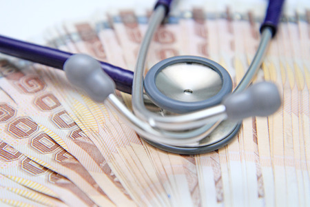 Close-up of stethoscope on top of banknotesの写真素材