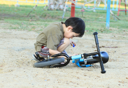 Asian boy looking his bicycle in the parkの写真素材