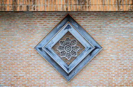 Perforated wood within wooden frame on old brick wall backgroundの写真素材