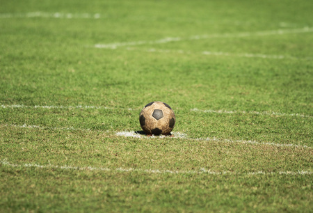 Old soccer ball on green grass fieldの写真素材