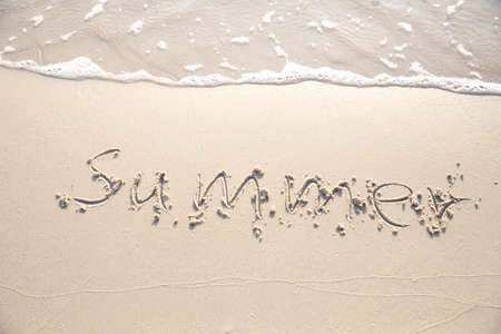 Word "Summer" hand written in the sand. Close up sand texture on beach in summer. Vacation, holiday concept,の写真素材