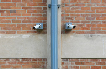 Two surveillance cameras installed on red brick wall.の写真素材