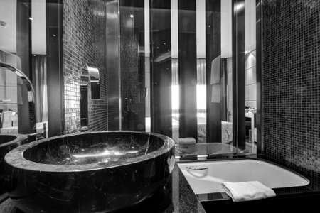 Black sink with chrome faucet  on marble plate in bathroomの写真素材