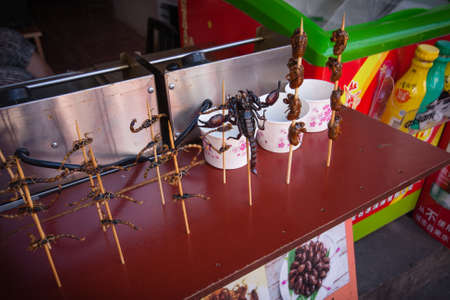 ZHUJIAJIAO, CHINA - AUGUST 30, 2016: Scorpions insects and bugs on spits are offered to shopping tourists as food by a vendor in the market street stall in Zhujiajiao, China, on August 30, 2016.のeditorial素材