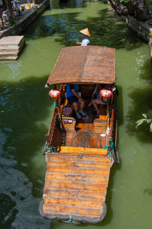 ZHUJIAJIAO, CHINA - AUGUST 30, 2016: Boatman transports tourists by Chinese gondola on canal of ancient water town with a history of more than 1700 years in Zhujiajiao, China, on August 30, 2016.のeditorial素材