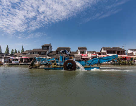 ZHUJIAJIAO, CHINA - AUGUST 30, 2016: Motorboat for cleaning underwater grass moves on canal of ancient water town with a history of more than 1700 years in Zhujiajiao, China, on August 30, 2016.のeditorial素材