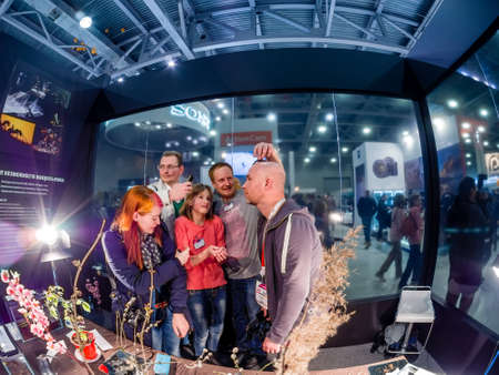 MOSCOW, RUSSIA - APRIL 21, 2017: Visitors take part in macro photography workshop at booth of Olympus company at PhotoForum 2017 trade show and exhibition in Moscow, Russia on April 21, 2017.のeditorial素材