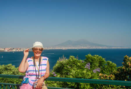 Happy mature tourist woman travelling in Italy with video camera on her neck on the Naples bay and Vesuvius mountain background.
の写真素材