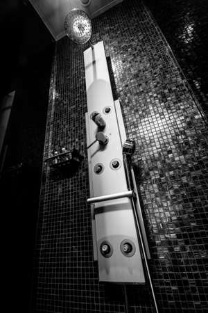 Chrome-plated sprinkle shower with sprayers and  tap for hot and cold water at the tiled wallの写真素材