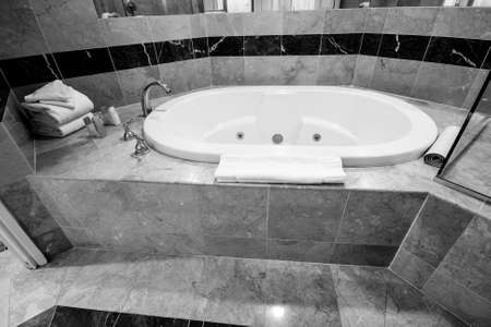 White bathtub and brass taps decorated with marble tiles