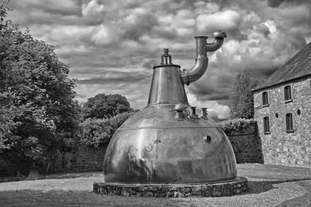 Old big copper whiskey distillery on stone foundation outdoorの写真素材