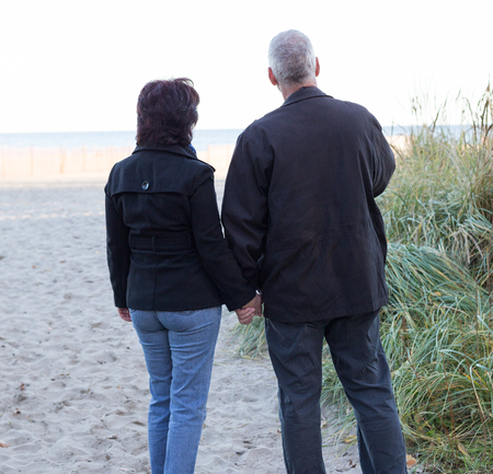 Couple watching sunset over the beach and holding hands.の写真素材