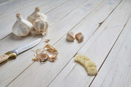 High-angle shot of a still life of some heads, some cloves and slices of garlic on a white wooden tableの写真素材