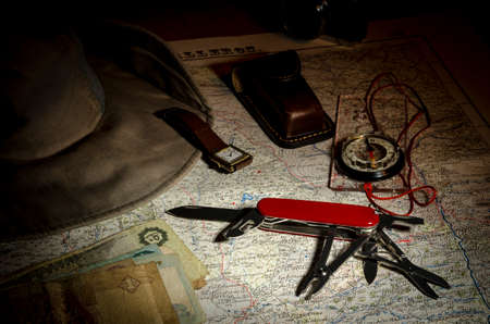 Multipurpose knife, compass, money and hat on an old map.の写真素材