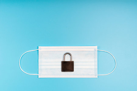 Medical mask and padlock. Concept of quarantine, protection, restriction from viruses and pandemic.の写真素材