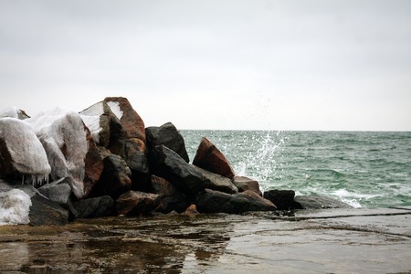 Winter Sea rocks and waves beat against the pier.の写真素材