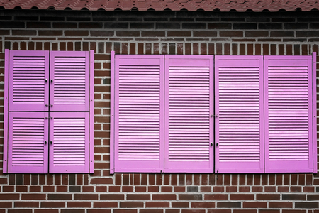 Red brick wall with a closed pink window.の写真素材