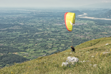 Paraglider starting a flight over the hills on a sunny dayの写真素材