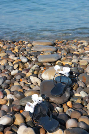 Black flip-flops on the beachの写真素材