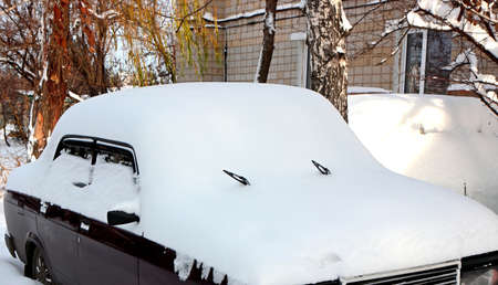 Car parked near a tree is covered with snowの写真素材
