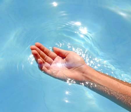 Hand on surface of water and sunlight glareの写真素材