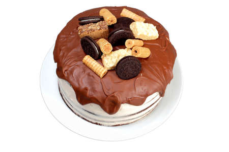 Cake, glazed with milk chocolate and decorated with waffles and cookies, on white plateの写真素材