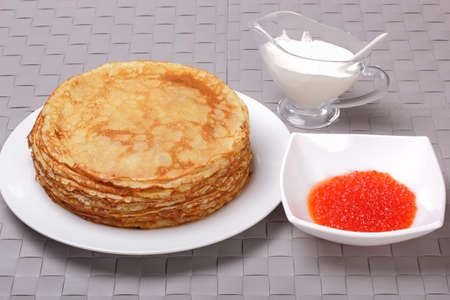 Pancakes, red caviar and sour cream on gray wicker backgroundの写真素材