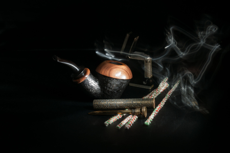 Pipe with a pipe-lighter and smoking accessories on a black backgroundの写真素材