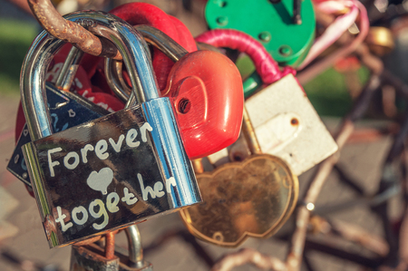Metallic shiny lock with the inscription forever together hanging among other heart-shaped locksのeditorial素材
