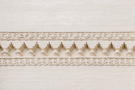 Repeating old traditional ornament on a plastered wall on a sunny day with shadowsの写真素材