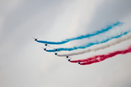 Several military aircraft symmetrically perform aerobatics figures releasing a multicolored smokeの写真素材