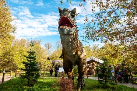 Russia, Moscow - September 29, 2018: Dinosaur carnotaur. Model in full size against a background of trees in the parkのeditorial素材