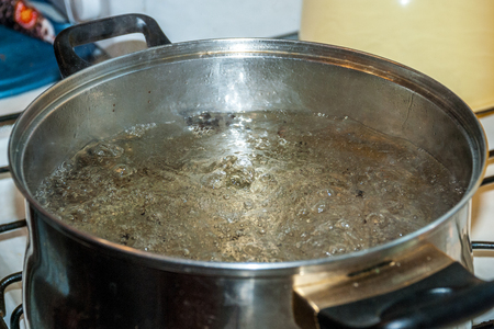 Boiling water for spaghetti or soup in a stainless steel pan on the kitchen stove at homeの写真素材