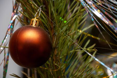 Old brown bright christmas ball on spruce branch close-up. Background for a greeting card.の写真素材