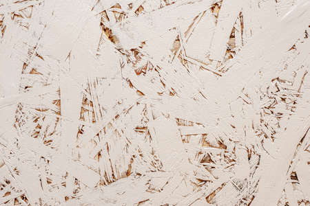 A board made of randomly arranged pressed shavings with a good detailed texture, painted in a light beige colorの写真素材