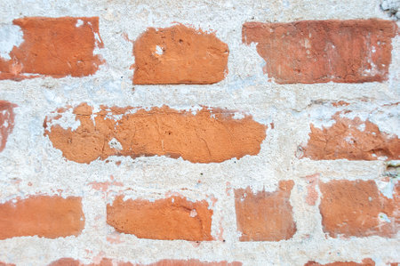 Empty old brick wall. Piece of texture, detail, part. Distressed surface of an old wall with wide bricks and damaged plasterの写真素材