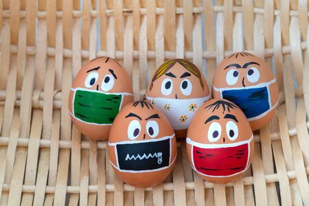 Easter eggs in medical masks lie on the bottom of the basketの写真素材