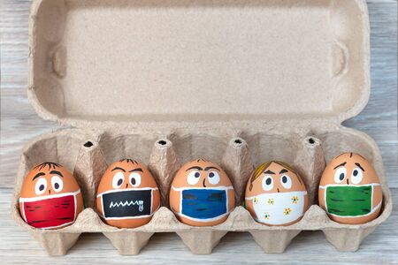 Easter eggs in medical masks lie in the trayの写真素材