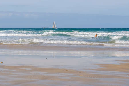 Port Elizabet, South Africa - September 12: Sailing vessel and boy with surfboard on the sea in the...