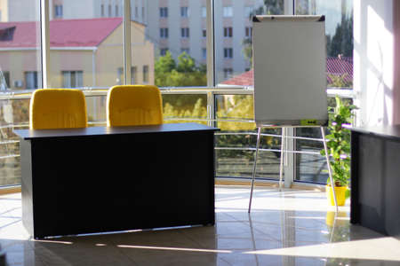 Business office with glass wall, black table, yellow chair and beautiful viewの写真素材