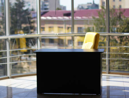 Business office with glass wall, black table, yellow chair and beautiful viewの写真素材