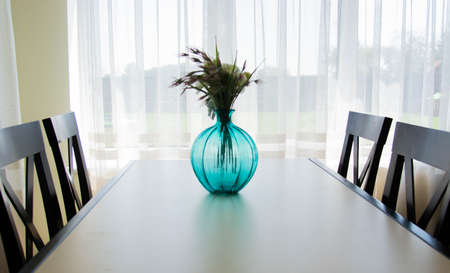 Blue vase standing on wooden table in the kitchen Modern white u-shaped kitchen in scandinavian style. Good morning. Natural lightの写真素材