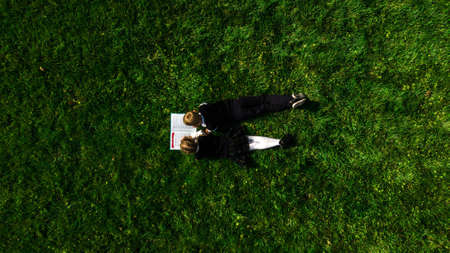 Children, in school form, reading the book on the grass in summer. Top viewの写真素材