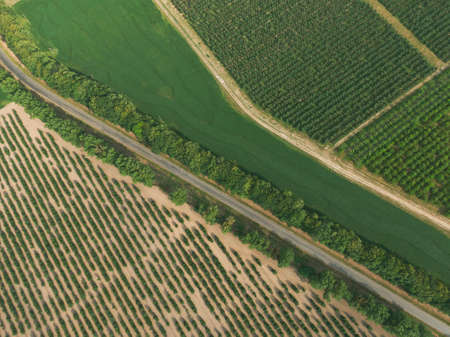 Aerial panorama of the road, that leads between green patterns of fields and gardens. Ukraine, Europeの写真素材