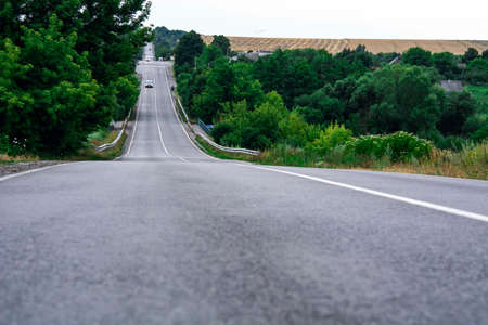 Driving on an empty road with white road marking and green trees on the sidesの写真素材