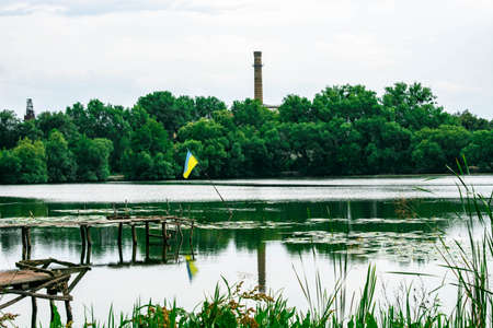 flag of Ukraine in the water near the broken wooden pierの写真素材