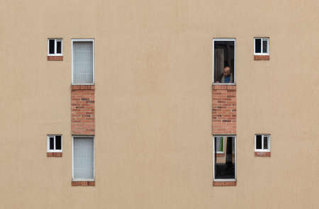 An old man look at the empty street through the window, in fisrt day of obligatory quarantine decreed by the government in capital city due to COVID19 pandemicのeditorial素材