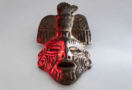 An ancient ceramic pre columbus mask based in American indigenous tribes art illuminated by red light over black backgroundの写真素材